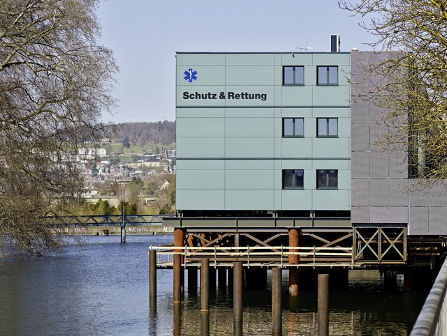 Limmatprovisorium, Zürich - Seitenansicht eines zweigeschossigen Holzmodulbaus auf einer Stahlbau Pfählung über dem Limmat Fluss