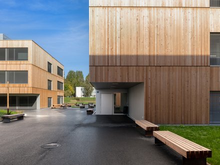 École professionelle de Vennes, Lausanne - Aussenansicht mit heller Holzfassade in Natur und grüner Wiese
