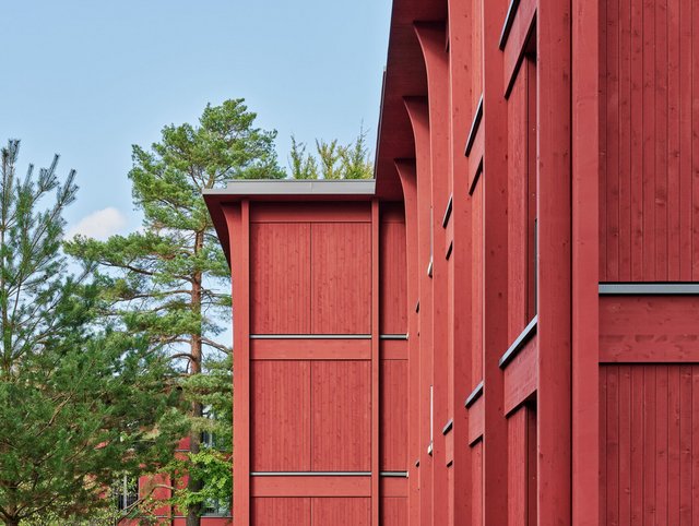 Hirtenweg, Riehen Hirtenweg, Riehen - Detailansicht der leuchtend roten Holzfassade mit grünen Bäumen im Hintergrund