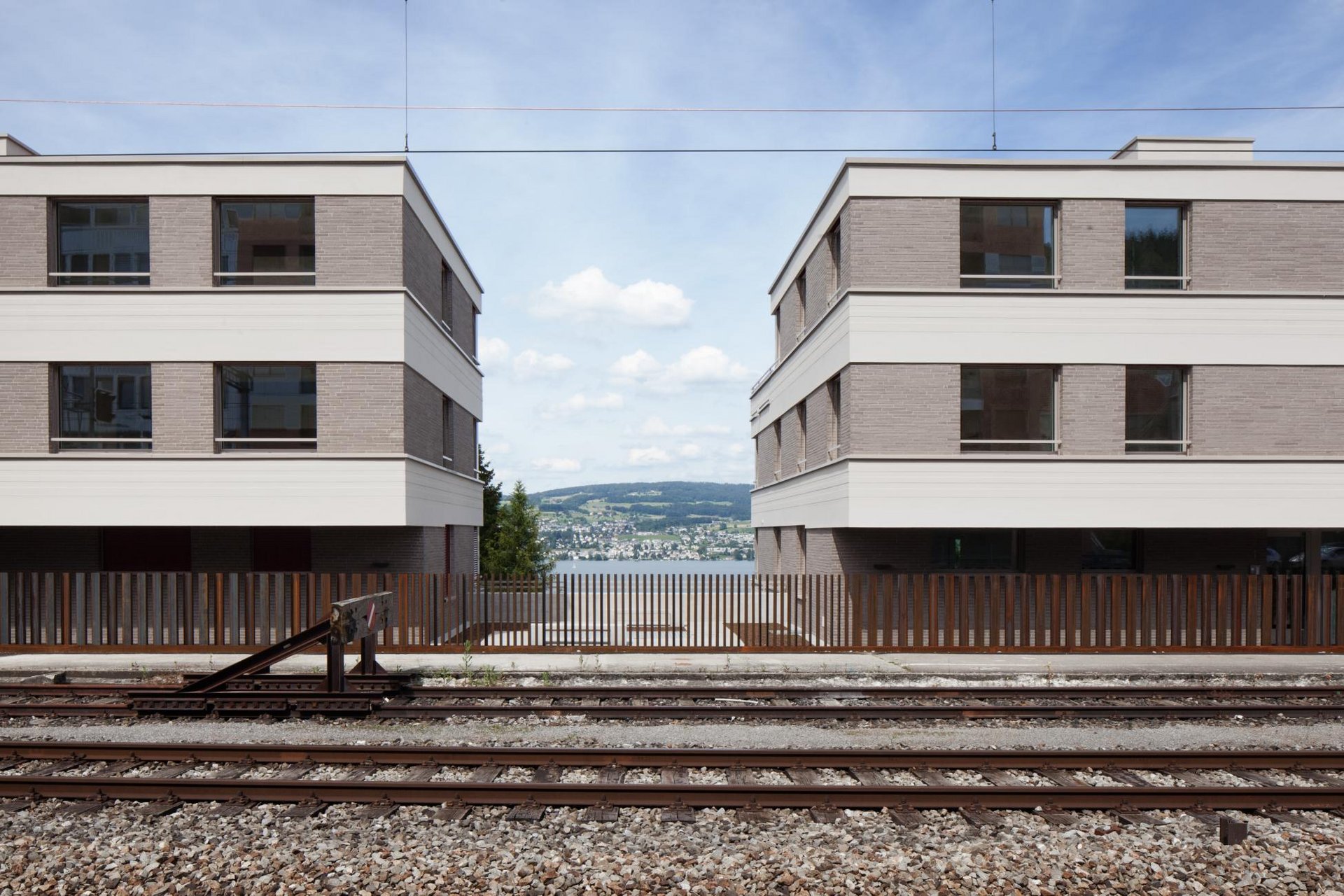 2 gleiche 2-stöckige Wohnblöcke mit gleichmässiger Fensteranordnung am Bahngleis