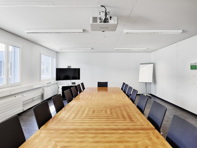 See-Spital, Horgen - Sitzungszimmer mit einem grossen Holztisch und schwarzen Stühlen herum.  