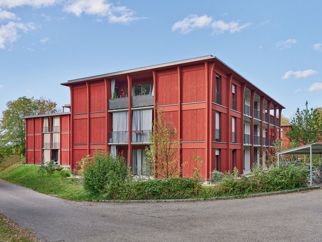 Hirtenweg, Riehen Hirtenweg, Riehen - Aussenansicht der gesamten Anlage mit drei Wohngebäuden all in leuchtendem rot in grüner, blühender Parkanlage