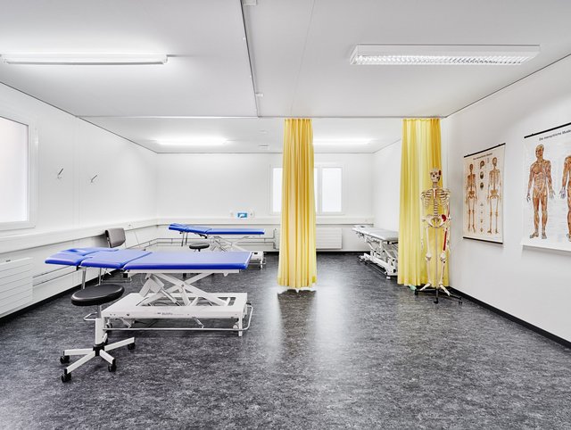 See-Spital, Horgen - Ein Untersuchungszimmer mit zwei Liegen, gelben Vorhängen und einem vorzeige Skelet. 