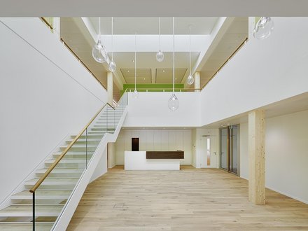 Betriebsgebäude Bio Familia, Sachseln - Heller Eingangsbereich eines Betriebsgebäudes mit Holzboden und Treppe in die obere Etage