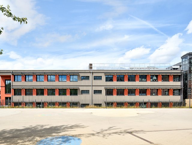 Albert Wingert Schule, Schifflange - Frontansicht des Gebäudes mit roter Fassade und grauen Fensterbänder