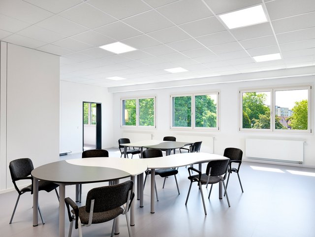 Europaschule, Kamp-Lintfort - Heller offener Raum mit Tischen und Stühlen. 