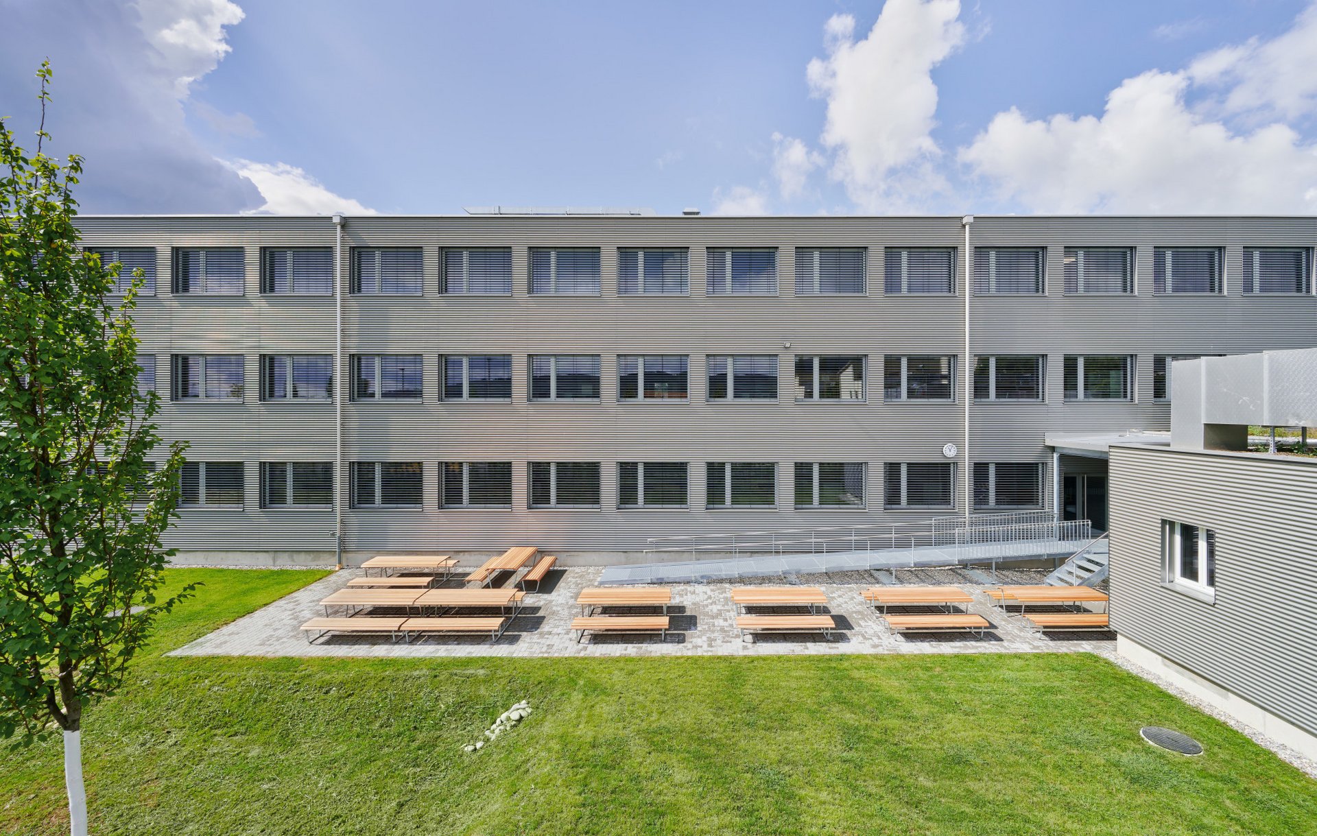 Frontale Ansicht auf das Gebäude, mit Aussenanlage. 