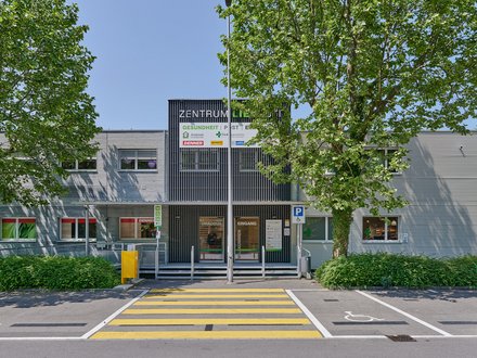 Einkaufszentrum Liebrüti, Kaiseraugst - Aussenansicht frontal des Eingangs mit dunkler Fassade und Bäumen