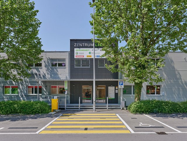 Einkaufszentrum Liebrüti, Kaiseraugst - Aussenansicht frontal des Eingangs mit dunkler Fassade und Bäumen