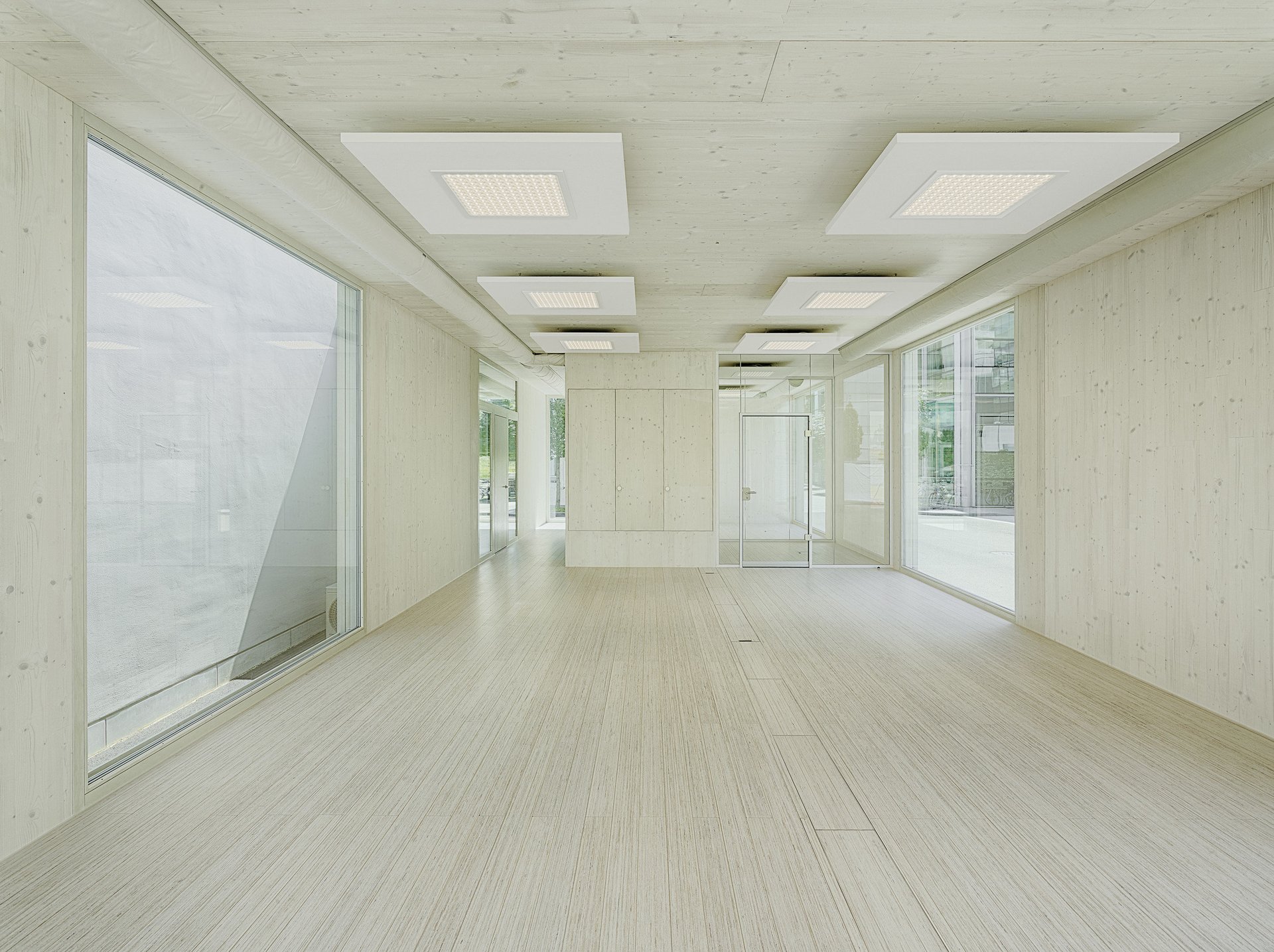 Leerer Raum aus sichtbarem Massivholz und beidseitig festverglasten raumhohen Fenster