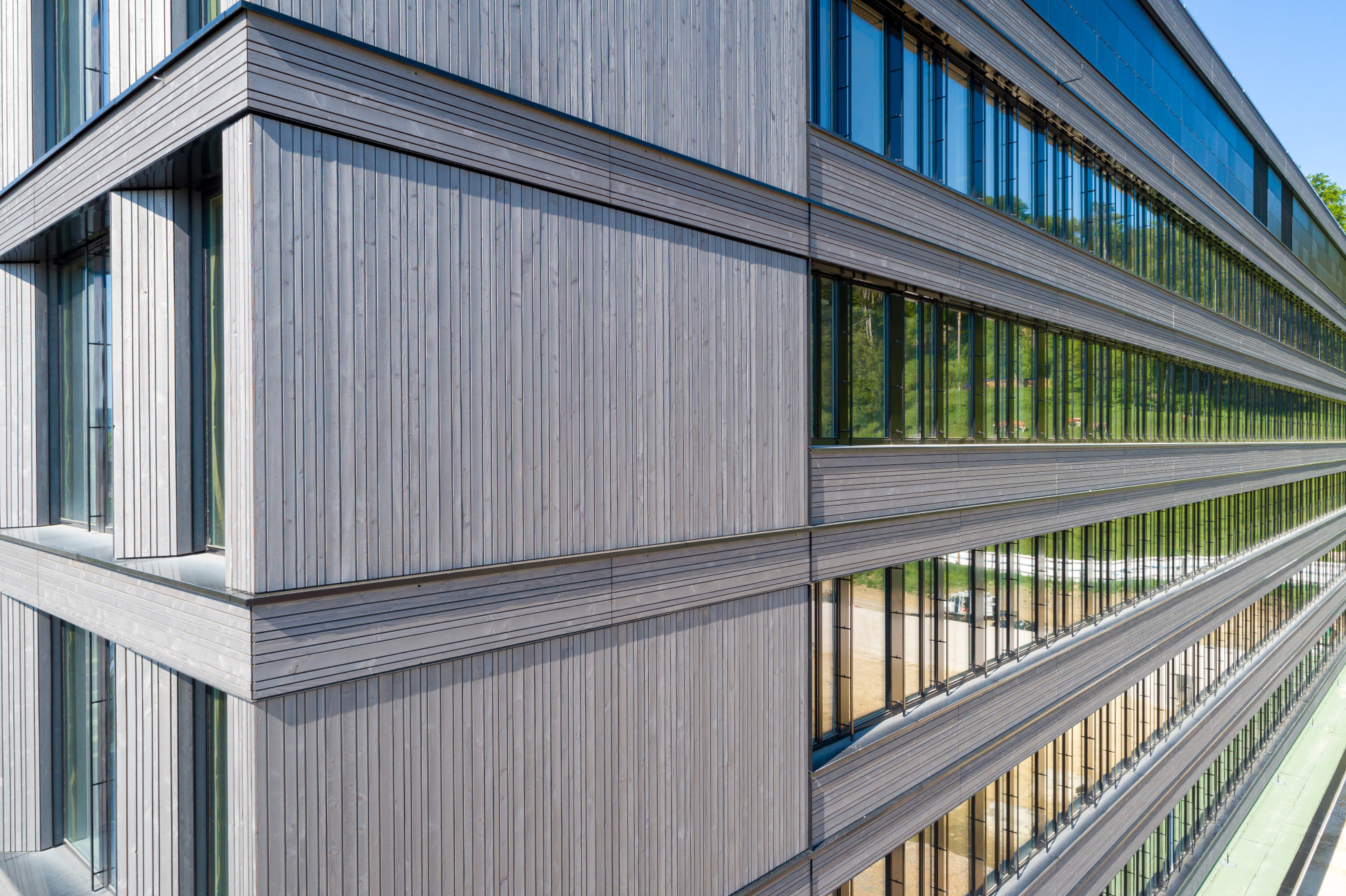 Gebäudekomplex mit grauer Fassade aus Holz und grossen Fenstern