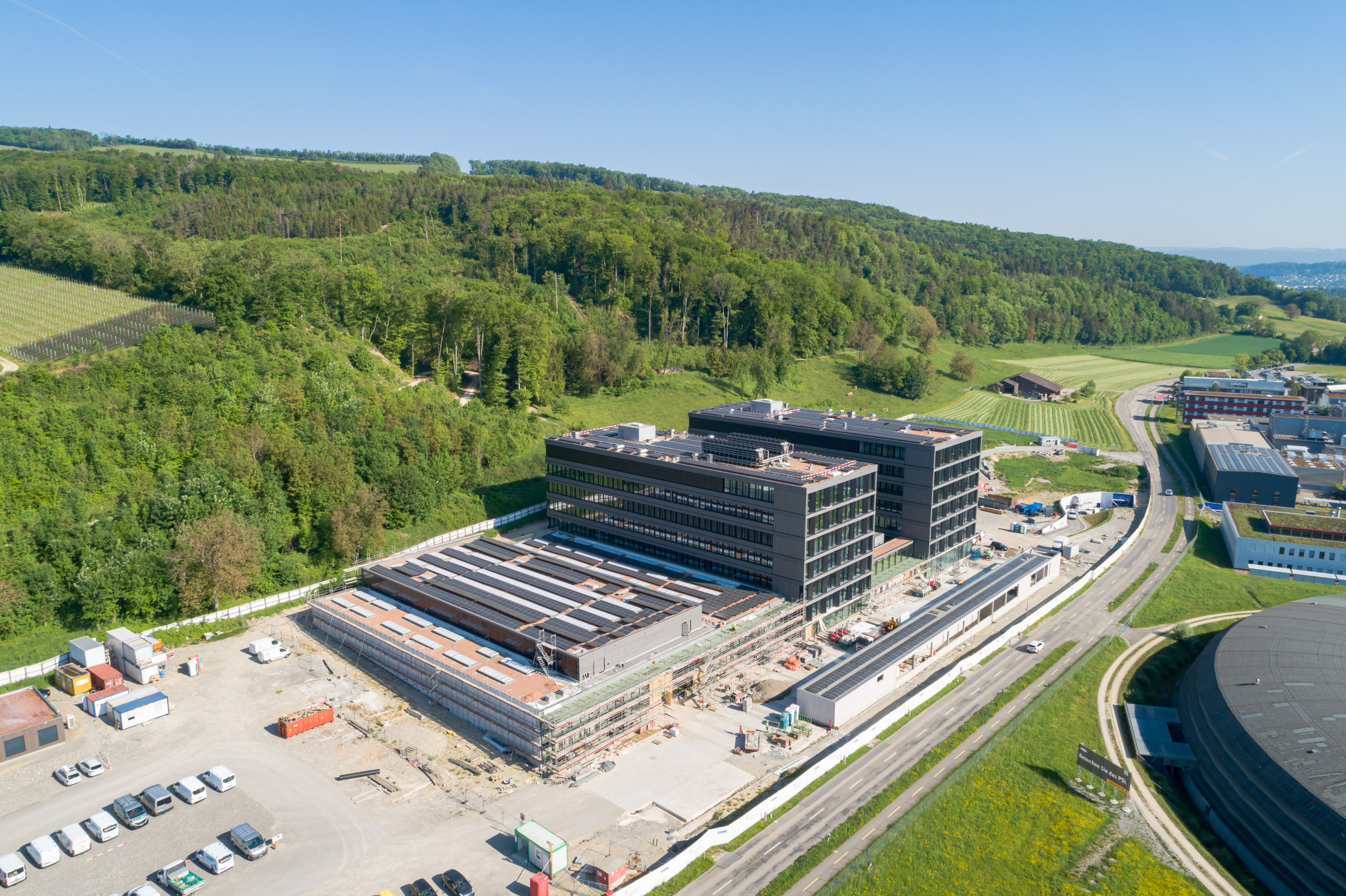 Drohnenaufnahme von einem grossen Gebäudekomplex mit Photovoltaik Panels auf dem Dach