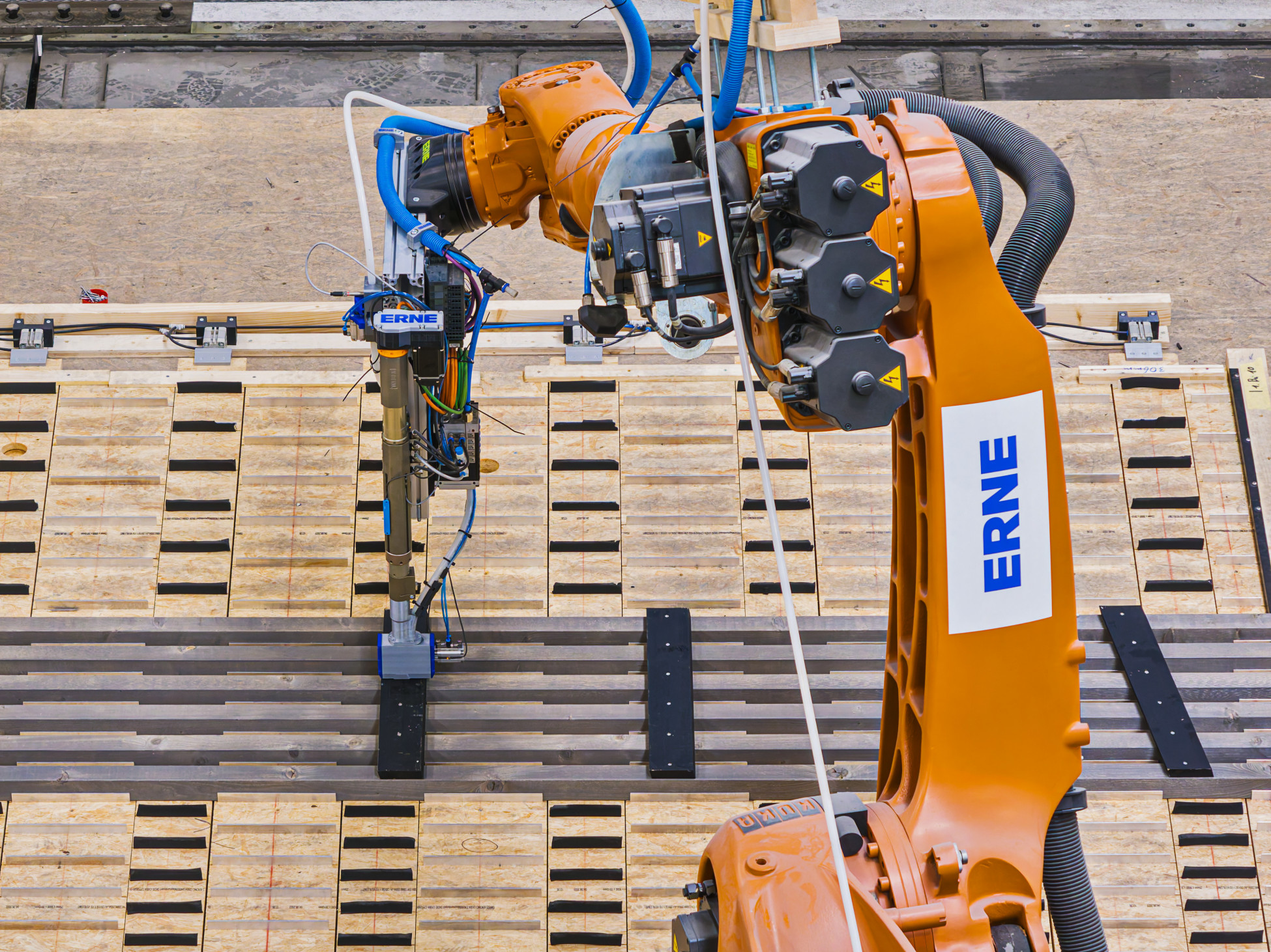 ERNE Fassadenroboter in orange fertigt ein Fassadenelement auf einer Schablone