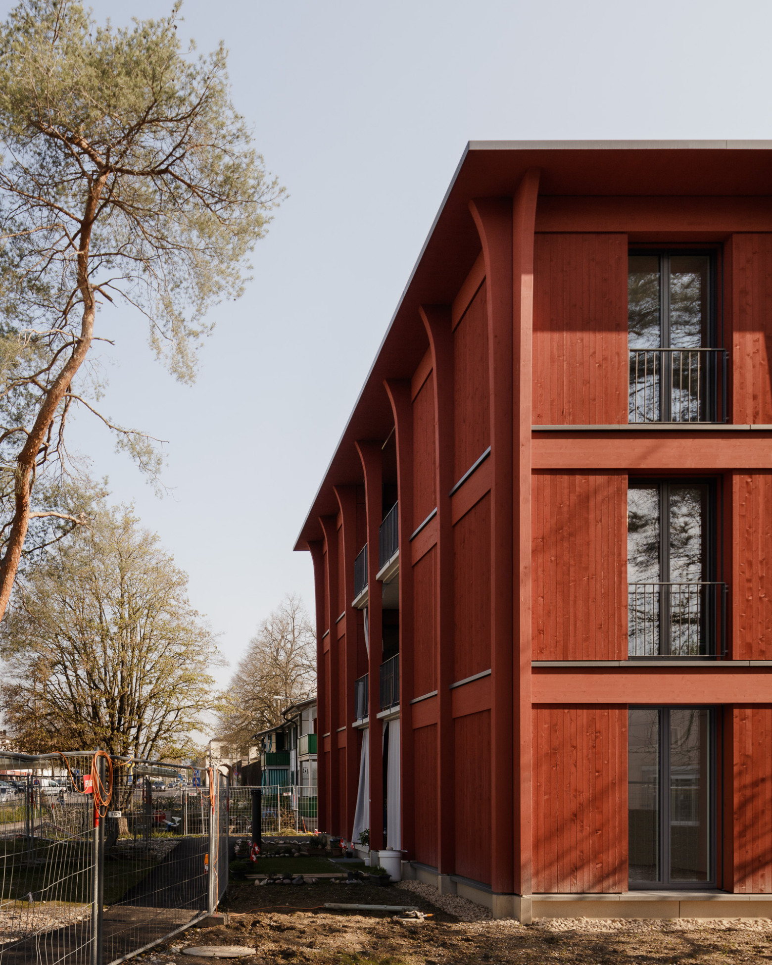 Hirtenweg, Riehen Hirtenweg, Riehen - Detailansicht Gebäudeecke mit Fassade in leuchtendem rot mit Parkanlage im Herbst